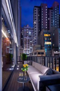 uma varanda com um sofá e uma mesa com copos de vinho em AKVO Hotel em Hong Kong