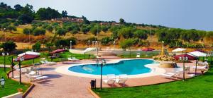 uma grande piscina com cadeiras e guarda-sóis em redor em Tenuta Bellaprima CALTAGIRONE em Niscemi