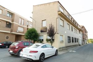 um carro branco e um carro vermelho estacionado em frente a um edifício em Hostal Legaz em Funes