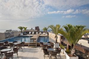 a rooftop patio with tables and chairs and a swimming pool at Residencial Budget in Rio de Janeiro