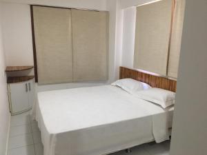 un letto bianco in una stanza con due finestre di Apartamento 01 Enseada Praia do Forte a Praia do Forte Altre 24 foto