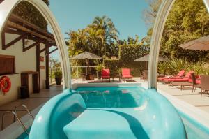 uma piscina com um pátio exterior com cadeiras e guarda-sóis em Hotel Marambaia Cabeçudas - frente mar em Itajaí