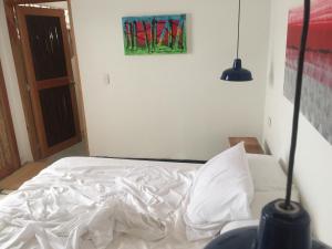 a white bed in a room with a painting on the wall at Casa de la tierra in Santa Marta