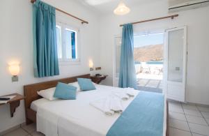 a bedroom with a large white bed with blue pillows at Miké Hotel in Aegiali