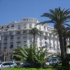 ein großes weißes Gebäude mit Palmen davor in der Unterkunft Studio Cannes Croisette in Cannes