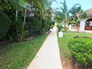 een loopbrug voor een huis met palmbomen bij Zanzibar Star Resort in Nungwi