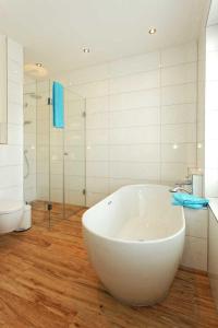 a bathroom with a large white tub and a toilet at Kapitaensweg 32 in Ostseebad Karlshagen +17 photos