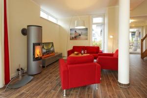 a living room with red furniture and a fireplace at Kapitaensweg 18 in Ostseebad Karlshagen