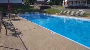 a large blue swimming pool with chairs and a table at Early American Motel in Aurora