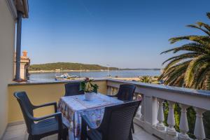 a table and chairs on a balcony with a view of the water at Andrino in Mali Lošinj