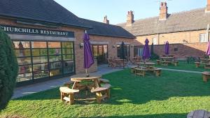 un grupo de mesas de picnic y sombrillas púrpuras en un patio en Blue Boar Inn, en Atherstone