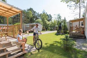 Una donna in bicicletta e una donna con un cane in mano di Strandcamping Gruber a Faak am See