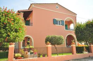 a pink house with a fence and trees at Elena Apartments Corfu in Acharavi