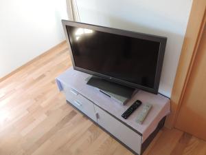 a flat screen tv on a dresser with a remote control at Cathares Holidays in Carcassonne