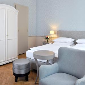 
a hotel room with a bed, chair, and desk at Hotel Kärntnerhof in Vienna

