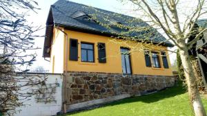 a yellow house with a stone wall at Schluchthäusl in Lunzenau