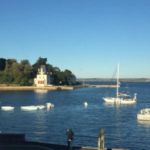 a sail boat in the water with a house and boats at Appartement Design V Port de Tréboul-Douarnenez in Douarnenez