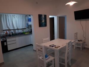 een keuken met een tafel en een witte tafel en stoelen bij Cabaña Siete Colores in Santa Rosa de Calamuchita