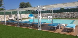 una piscina con sedie blu e un padiglione di Appartamenti in villa Alessia a Monopoli