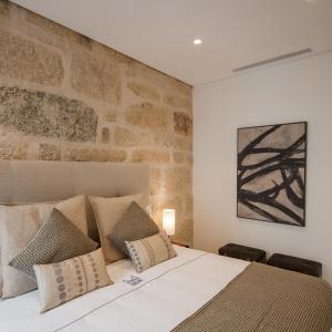 1 dormitorio con 1 cama grande y pared de piedra en Porto Deluxe Suites, en Oporto