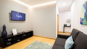 a living room with a couch and a tv on a wall at Bugalha My Loft Douro 4 in Peso da Régua
