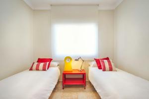 ロス・カーニョス・デ・メカにあるLa Casa Azul , sol, playa....relax.の赤と白の枕と赤のテーブルが備わるベッド2台