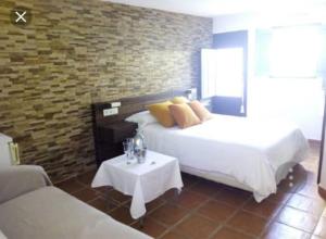 a bedroom with a bed and a table and a brick wall at La Trancada in Tabarca