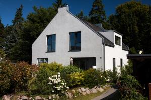 a white house with black windows in a garden at Ferienhaus Sonnensteg 23 in Ostseebad Sellin