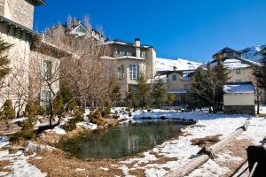 a river in the middle of a town with snow at Hotel Apartamentos Trevenque in Sierra Nevada