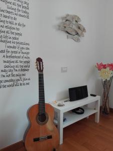 une guitare assise sur un mur à côté d'une télévision dans l'établissement Silos Torrenova, à Potenza Picena