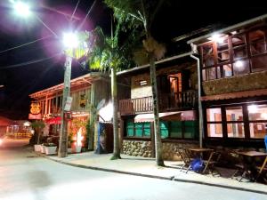 a building with palm trees on a street at night at Moradas Girassol in Guarda do Embaú
