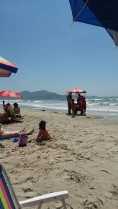 a group of people on a beach with umbrellas at Apartamento Itapema ou Meia Praia in Itapema