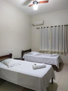 a room with two beds and a ceiling fan at Hotel London in Araraquara