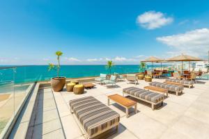a patio with chairs and tables and the ocean at Hyatt Place Macae in Macaé