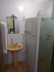 a bathroom with a sink and a shower with a mirror at Hotel London in Araraquara