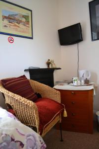 a bedroom with a chair and a dresser with a television at Knightsrest in Burnham on Sea