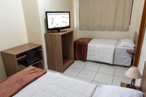 a hotel room with two beds and a flat screen tv at Hotel D'Nápoles in Ijuí