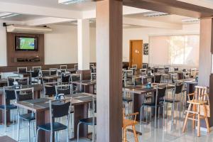 an empty room with tables and chairs and a projection screen at Hotel D'Nápoles in Ijuí