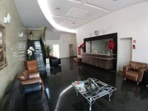 Lodi Express Hotel في Arapongas: غرفة معيشة مع أريكة وكراسي وطاولة