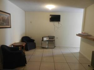 sala de estar con 2 sillas y TV en la pared en Consul Suites, en Ciudad Juárez