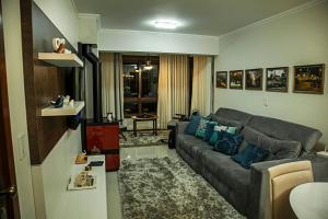 a living room with a gray couch and blue pillows at Ednamar Apartmentos Gramado Siena in Gramado