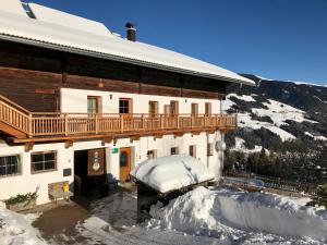 a building with a balcony on top of snow at Bleierhof Apartment in Kartitsch