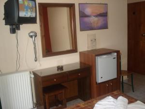 Habitación con TV y tocador con espejo. en Apolis hotel, en Mouzákion