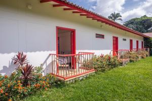 a white building with a red door and a yard at Hacienda Venecia Coffee Farm Hotel in Manizales
