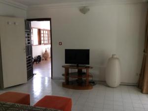 sala de estar con mesa y TV en Hôtel le Flamboyant, en Abiyán