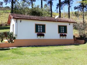 a small white house with two windows at Recanto Das Borboletas in São Roque