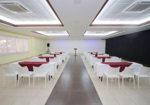 Mar & Sol, Hotel y resturante في لا يونون: غرفة بها صفوف من الطاولات والكراسي البيضاء