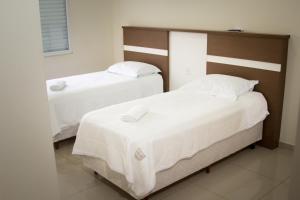 two beds in a room with white sheets at Hotel Rio Fortuna in Rio Fortuna