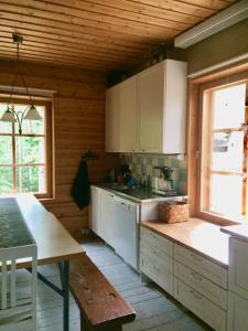 a kitchen with white cabinets and a table in it at Seitsemisen Torpat Log Cabin in Latovesi