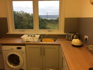 a kitchen with a sink and a washing machine at Ardminish House Gigha in Isle of Gigha